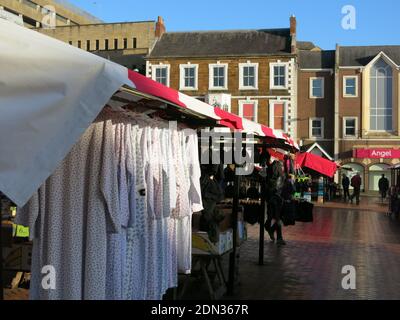 With its origins in medieval times, Northampton's Market Square continues to this day with a colourful awning over this stall selling nightdresses. Stock Photo