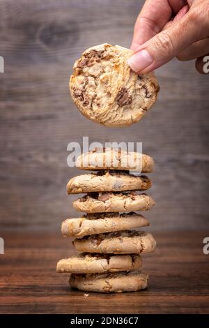 Human hand taking a chocolate chip cookie cookie from a stack Stock Photo