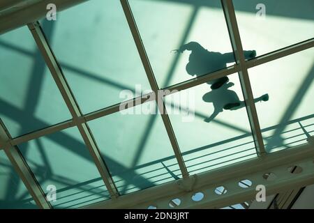 View from underneath at shadow of a couple walking on a glass bottom walkway in shopping mall, Lisbon, Portugal Stock Photo