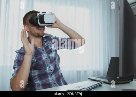 Happy bearded man using virtual reality goggles, copy space. Cheerful male student having fun, using vr headset, resting after studying Stock Photo