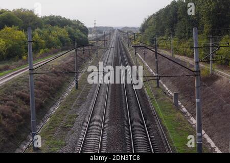 Railway, view from the top. The rails go into the distance beyond the horizon. Two pairs of railways run straight. Stock Photo