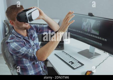 Cheerful man smiling, trying 3D vr goggles, taking a break from working online. Happy man relaxing at home, using virtual reality glasses Stock Photo