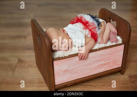 Photoshoot of a newborn in a wooden crib. The girl sleeps in a small crib Stock Photo