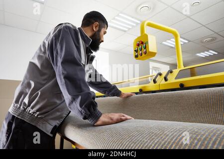 Man operating carpet automatic washing machine in professional laundry service Stock Photo