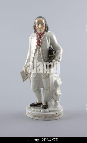 Figure, Molded, glazed and gilt earthenware, Statuette of Benjamin Franklin standing before a tree-stump, holding a tricorne hat against his left hip, a document in his right hand. Clothing is white with details in gold; a red scarf at his neck. A round base with the gilded inscription: The old English Gentleman, England, mid- 19th century, ceramics, Decorative Arts, Figure Stock Photo