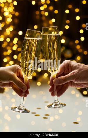 Man and woman hands brings glasses of champagne on festive lights background Stock Photo