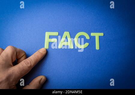 Human finger pointing the word Fact written with plastic letters on blue paper background, concept Stock Photo