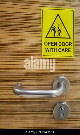 A safety placard near door handle to open up with care. Stock Photo