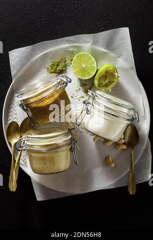 different types of sauces in glass jars. with pistachios, cashews and vegan mayo. Stock Photo