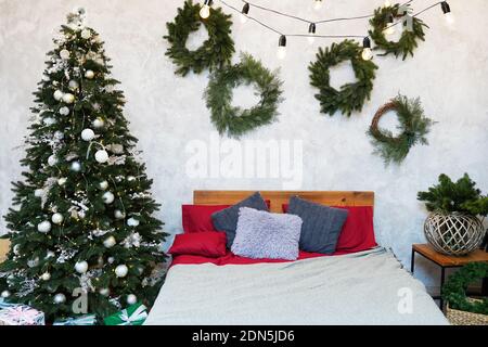 New Year's interior. Christmas tree near bed with pillows. Concept happy Cristmas Stock Photo