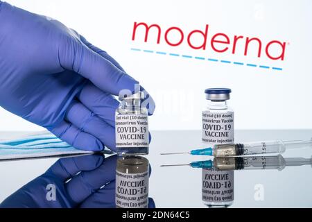 Morgantown, WV - 16 December 2020: Small bottle of coronavirus vaccine with syringe with background of Moderna logo Stock Photo