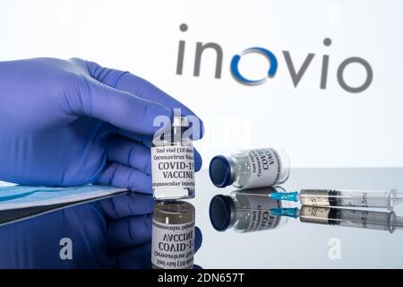 Morgantown, WV - 16 December 2020: Small bottle of coronavirus vaccine with syringe with background of Inovio logo Stock Photo