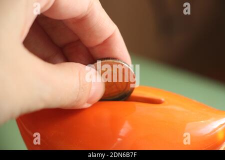 Hand puts euro coin in saving moneybox. Money saving and investment financial concept. Stock Photo