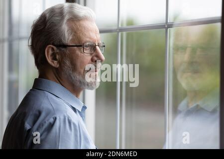 Pensive elderly mature senior man in eyeglasses looking in distance. Stock Photo