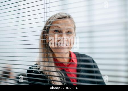successful business woman looks through an office window Stock Photo