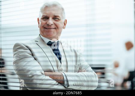 smiling Mature businessman looking through office window blinds. Stock Photo