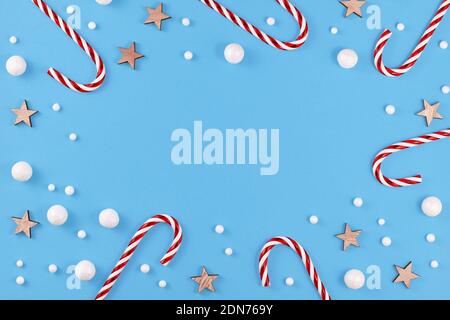 Christmas flat lay with candy canes, stars and snowballs on blue background with empty copy space in middle Stock Photo
