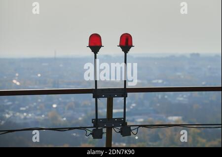 Red warning warning light with the light on, against the blue sky. explosive plant area. red lights on the roof of high-rise building for the safety o Stock Photo