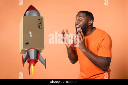 Amazed and shocked expression of a boy who receives a package. orange background Stock Photo