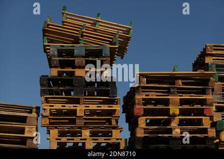Low Angle View Of Stacked Wooden Pallets Against Clear Blue Sky