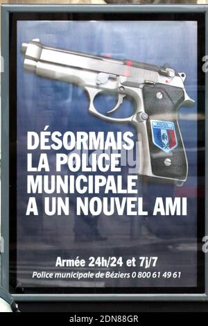 A municipality campaign poster shows an automatic 7.65 handgun, with the badge of the French Republic on its grip. Since February 1, the Beziers municipal police is equipped with lethal weapons, in this case automatic 7.65 handguns, and nine armed police officers already patrol the streets, mostly at night, of the town whose far-right party National Front-backed mayor Robert Menard was elected last year. The campaign slogans read : 'From now on, the Municipal Police has a new friend', and 'Armed 24 hours a day, 7 days a week'. Menard is no stranger to controversy after he banned halal meals in Stock Photo