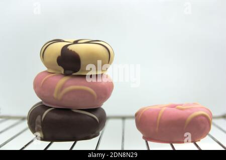 Still life of donuts of various colors and flavors on a grill on white background Stock Photo