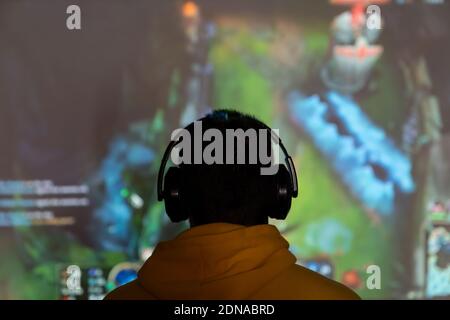 Gamer wearing headphones playing in front of a screen Stock Photo