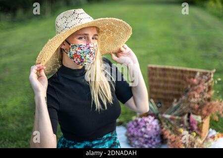Beautiful young woman wearing a stylish fashionable coronavirus face mask covering during Covid-19 pandemic lockdown Stock Photo