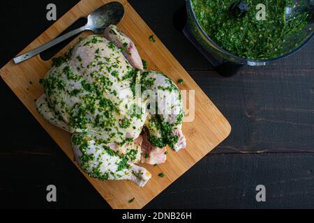 Basting a Raw Chicken in Chimichurri Sauce: Coating a whole chicken in freshly made chimichurri sauce Stock Photo