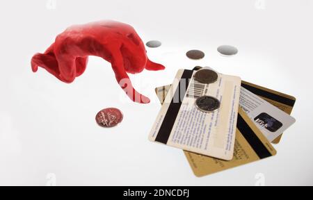 A modelling clay character worships to a few pennies and some credit cards.. Stock Photo