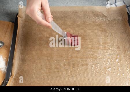 Greasing a baking sheet covered with baking paper Stock Photo