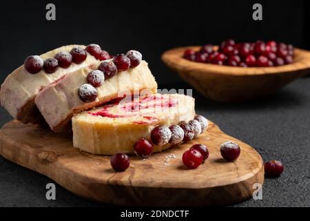 Homemade biscuit sweet roll with cranberries and cream on a black table Stock Photo