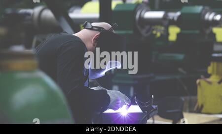 professional weld worker while using TIG Welding, wearing safety protective mask in selective focus view. Gas tungsten arc welding GTAW torch welder b Stock Photo