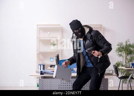 Young male burglar in the office room Stock Photo