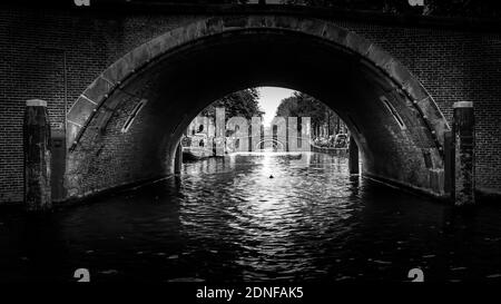 Black and White photo of View of seven historic bridges in a straight line over the Reguliersgracht, viewed from a canal boat in the Herengracht Stock Photo