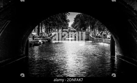 Black and White photo of View of seven historic bridges in a straight line over the Reguliersgracht, viewed from a canal boat in the Herengracht Stock Photo