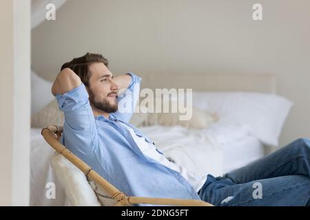 Relaxed young man sitting on cozy armchair. Stock Photo