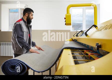 Man operating carpet automatic washing machine in professional laundry service Stock Photo