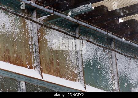 Snow clings to the side of an elevated train trestle, making a sharp contrast against the rusty patina, in the Bronx, NY Stock Photo