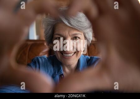 Close up happy middle aged beautiful woman making heart gesture. Stock Photo