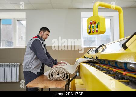 Man operating carpet automatic washing machine in professional laundry service Stock Photo
