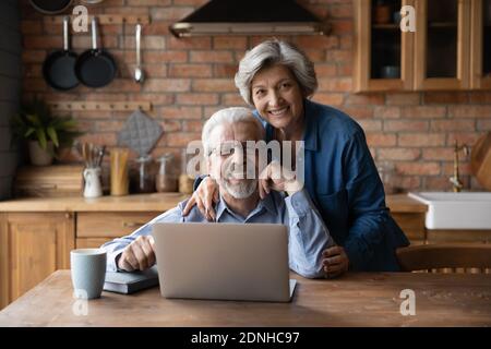 Happy middle aged family couple enjoying using computer applications. Stock Photo