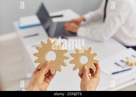 Company manager holding two cogwheels as metaphor for effective business management Stock Photo