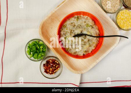 Cooked Dalia in orange Bowl, capsicum  and red chilli flakes in  glass bowl. Bulgar wheat, Broken wheat or cracked wheat or couscous is made by millin Stock Photo