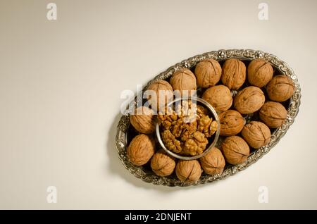 Walnut rich in omega-3 fats with shell and unshelled walnut kernel presented in a silver plate. Top angle. Studio Shot Stock Photo