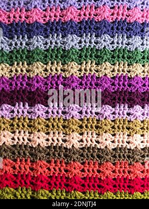 Craft or hobby background of a multi coloured crocheted or knitted blanket showing stitching detail with copy space Stock Photo