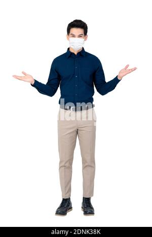 Young Asian businessman wearing face mask to protect from COVID19 doing open palms gesture in white isolated background Stock Photo