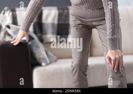 Man getting up from couch and holding on to sore knee closeup Stock Photo