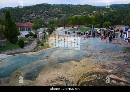 Karahayit, Pamukkale / Denizli, Turkey - September, 2018: Clear warm water in red travertine terraces. Hot springs terraces view. Turkish tourist peop Stock Photo