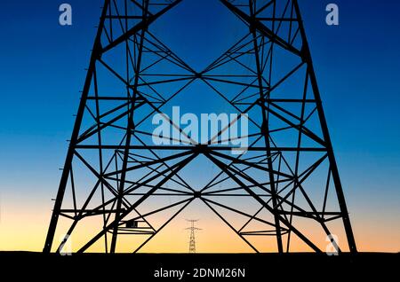 Power lines silhouetted against a vibrant sunset sky near forest Stock ...